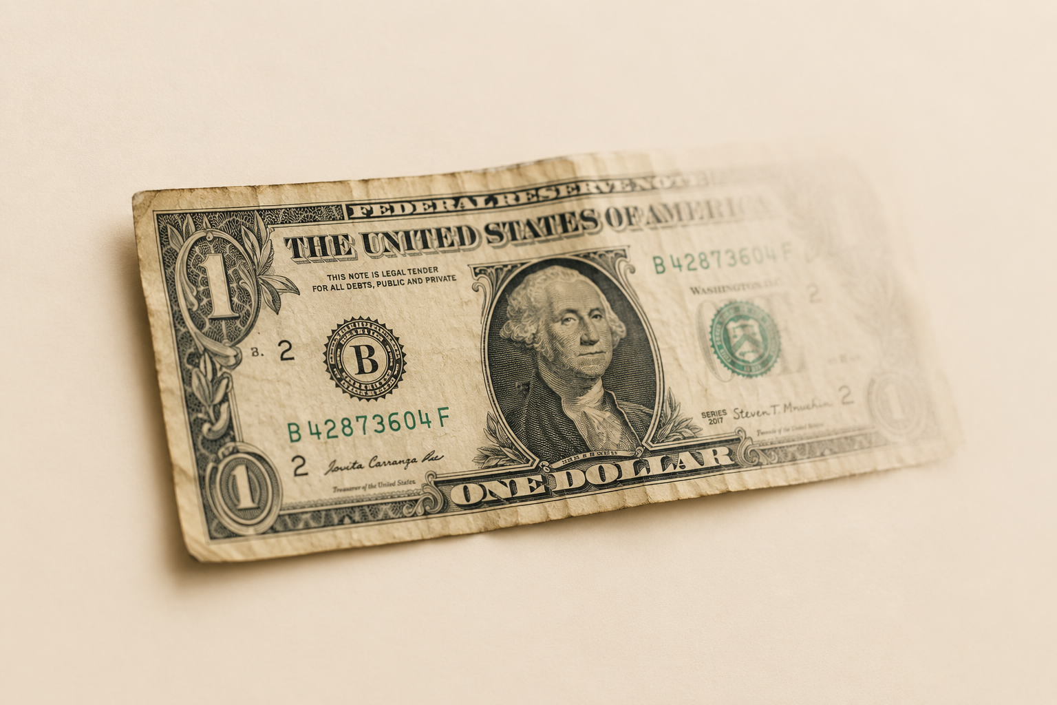A single aged US one dollar bill on a cream background